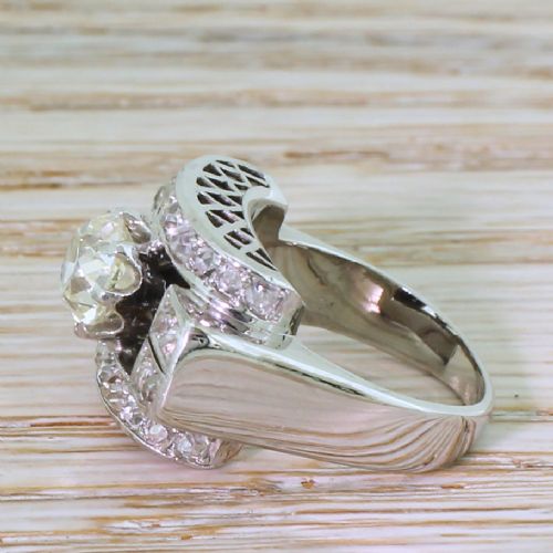 fig 2. An Art Deco diamond ring featuring a central round old European cut diamond set within an architectural rectangular metal frame surrounded by accent diamonds.