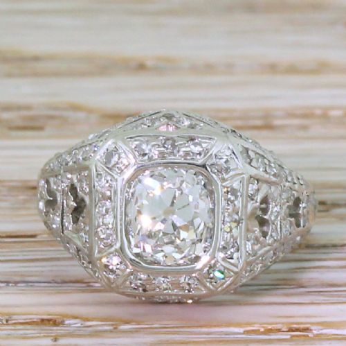 fig 1. An Art Deco platinum ring featuring a central cushion-shaped old cut diamond set within an openwork dome of pierced filigree and accent diamonds.