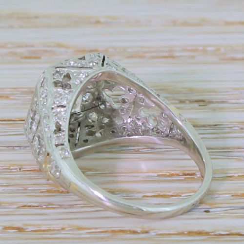 fig 3. An Art Deco platinum ring featuring a central cushion-shaped old cut diamond set within an openwork dome of pierced filigree and accent diamonds.