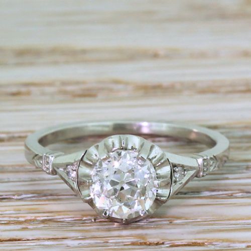 fig 1. An Art Deco diamond ring featuring a central round old cut diamond in a fluted platinum setting with geometric shoulders.