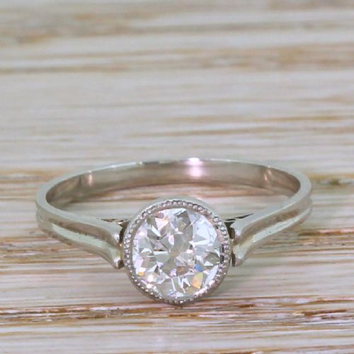 fig 1. An Art Deco solitaire engagement ring featuring a round old cut diamond set in a milgrained rubover bezel on a platinum band.