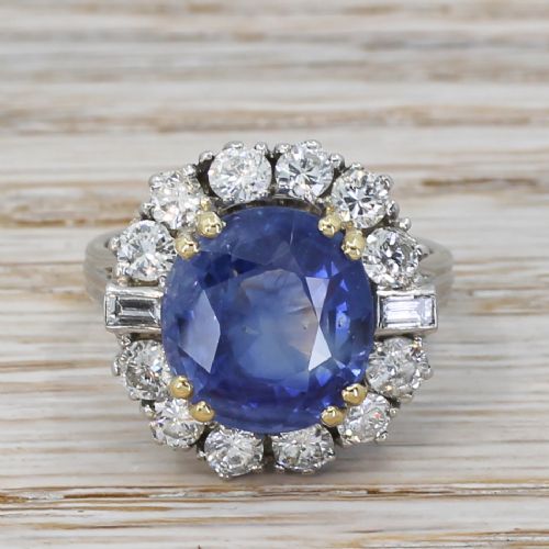 fig 1. A mid-century cluster ring featuring a central oval blue sapphire surrounded by round brilliant and baguette diamonds set in platinum.
