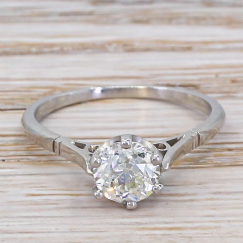 fig 1. An Art Deco diamond engagement ring featuring a central round old cut diamond held in six claws on a slender platinum band with carved geometric shoulders.