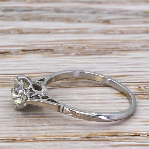 fig 2. An Art Deco diamond engagement ring featuring a central round old cut diamond held in six claws on a slender platinum band with carved geometric shoulders.