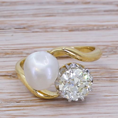 fig 1. An Edwardian yellow gold crossover ring set with a natural white pearl and a round old cut diamond on a curved band.
