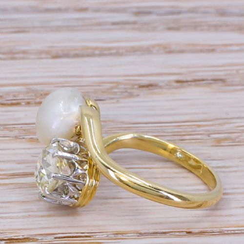 fig 2. An Edwardian yellow gold crossover ring set with a natural white pearl and a round old cut diamond on a curved band.