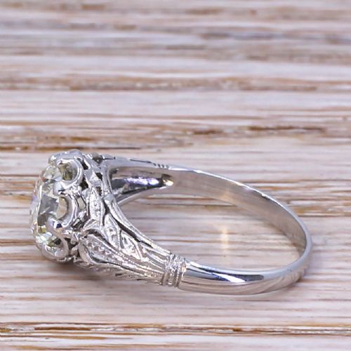 fig 2. A mid-century solitaire ring featuring a central round old-cut diamond set in a multi-claw platinum mounting with carved foliate shoulder details.