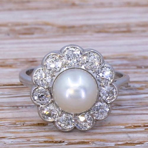 fig 1. An Art Deco ring featuring a central white natural pearl surrounded by a scalloped halo of old cut diamonds set in white metal.