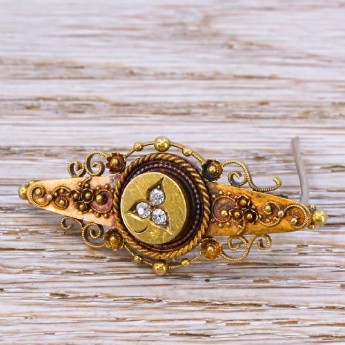 fig 1. A late Victorian gold bar brooch featuring filigree wirework, beaded accents, and three star-set diamonds in a central circular plaque.