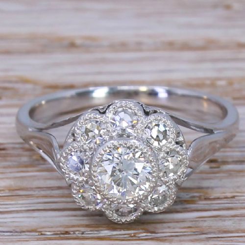 fig 1. A mid-century white metal ring featuring a central round diamond surrounded by a floral cluster of smaller old cut diamonds with millegrain edges.