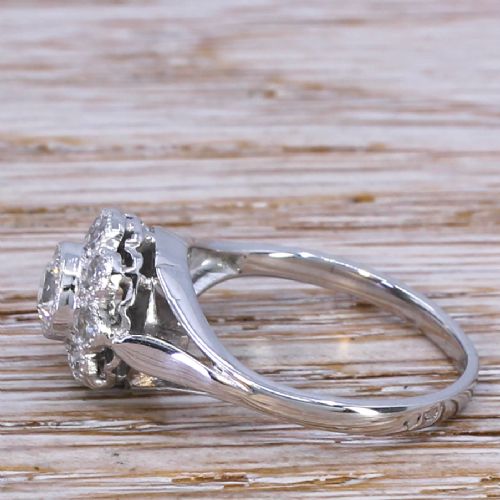 fig 2. A mid-century white metal ring featuring a central round diamond surrounded by a floral cluster of smaller old cut diamonds with millegrain edges.