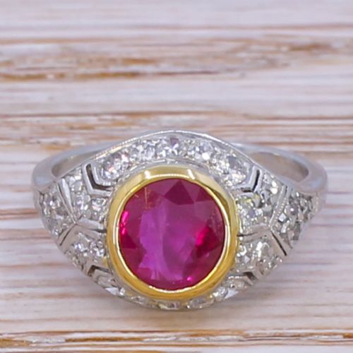 fig 1. An Art Deco ring featuring a round red ruby set in a gold bezel, framed by platinum geometric shoulders set with pave diamonds.