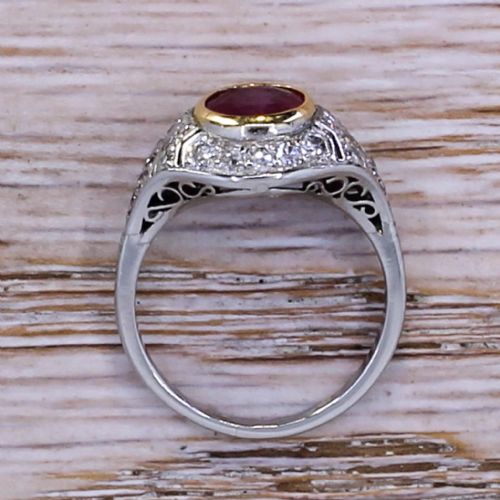 fig 4. An Art Deco ring featuring a round red ruby set in a gold bezel, framed by platinum geometric shoulders set with pave diamonds.