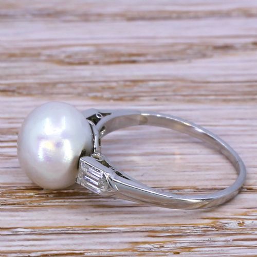 fig 2. An Art Deco solitaire ring displaying a round white natural pearl flanked by geometric shoulder diamonds set in a platinum band.