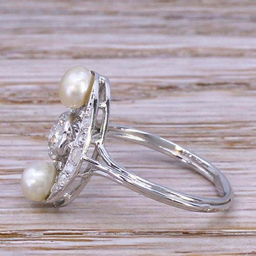 fig 2. A mid-century platinum dress ring featuring a central bezel-set round diamond flanked vertically by two white pearls inside an openwork oval diamond-set frame.