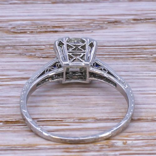 fig 3. An Art Deco diamond solitaire ring set in white metal featuring calibre-cut sapphire shoulders and engraved metalwork.