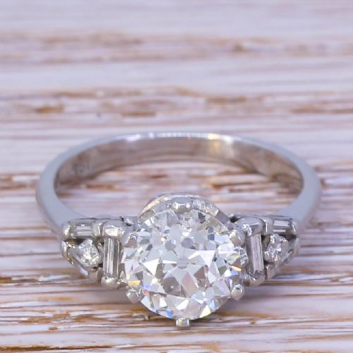 fig 1. A mid-century white gold engagement ring featuring a central round old-cut diamond flanked by baguette and small round accent diamonds on the shoulders.