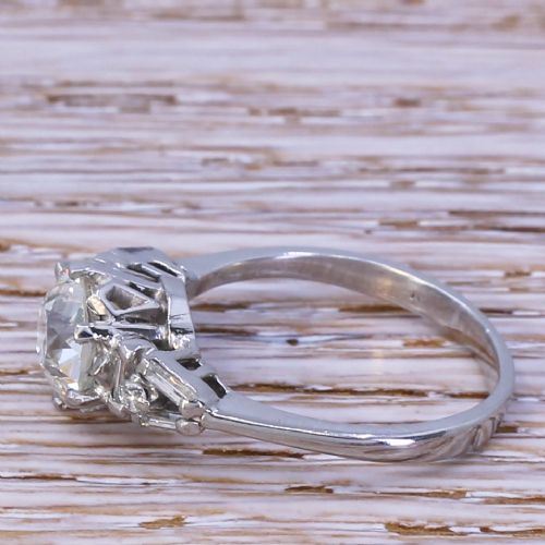 fig 2. A mid-century white gold engagement ring featuring a central round old-cut diamond flanked by baguette and small round accent diamonds on the shoulders.