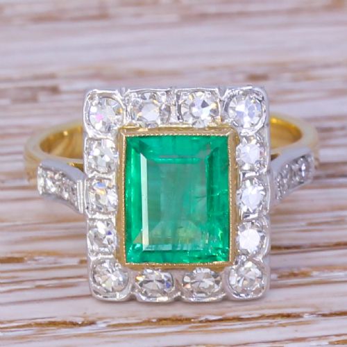 fig 1. An Art Deco ring featuring a rectangular emerald framed by a halo of diamonds set in platinum with a yellow gold band.