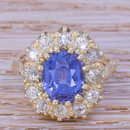 fig 1. A mid-century yellow gold cluster ring featuring an oval blue sapphire encircled by a halo of round diamonds.