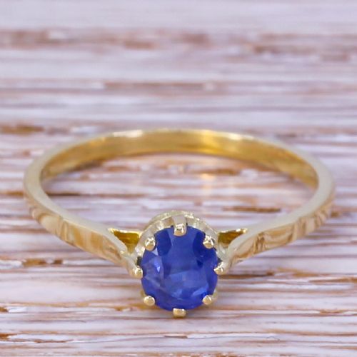 fig 1. A yellow gold ring featuring a single round-cut blue sapphire set within an eight-claw coronet mount.