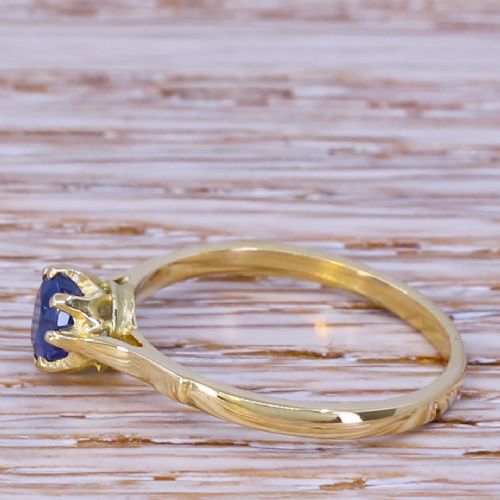 fig 2. A yellow gold ring featuring a single round-cut blue sapphire set within an eight-claw coronet mount.