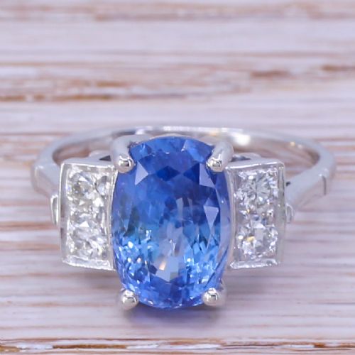 fig 1. A mid-century platinum ring featuring an oval cut blue Ceylon sapphire in a four claw setting flanked by rectangular diamond set shoulders.