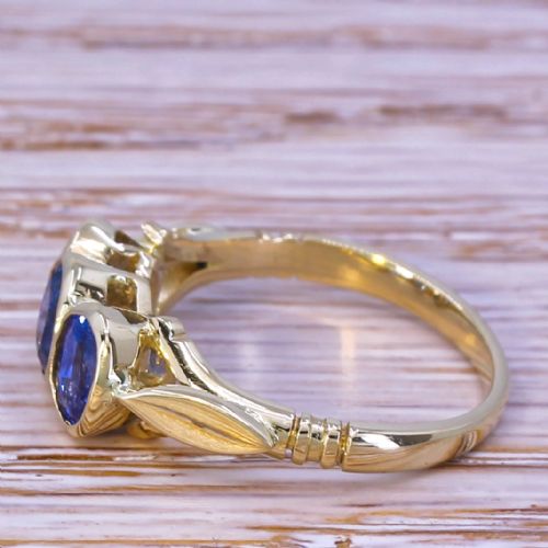 fig 2. A Victorian yellow gold trilogy ring featuring three oval-cut blue sapphires set in bezel mounts along a carved band.