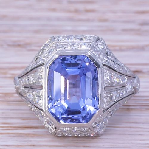 fig 1. An Art Deco platinum dress ring featuring an emerald cut blue sapphire surrounded by a geometric mounting set with small diamonds.