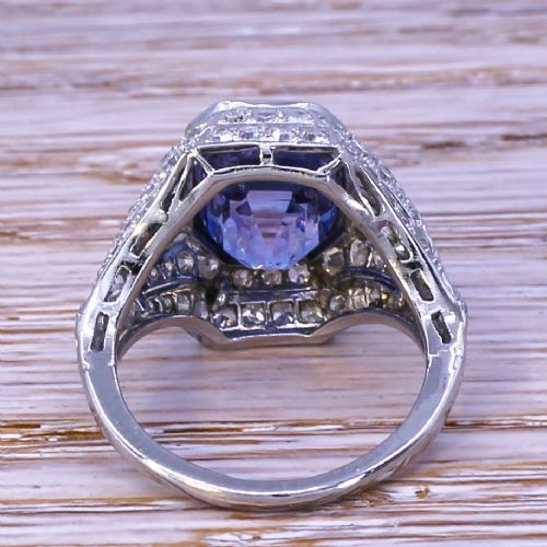 fig 3. An Art Deco platinum dress ring featuring an emerald cut blue sapphire surrounded by a geometric mounting set with small diamonds.