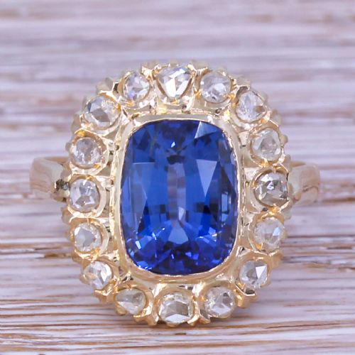 fig 1. An Art Deco yellow gold ring featuring a central cushion-cut blue sapphire framed by a halo of small diamonds.