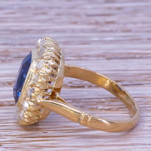 fig 2. An Art Deco yellow gold ring featuring a central cushion-cut blue sapphire framed by a halo of small diamonds.