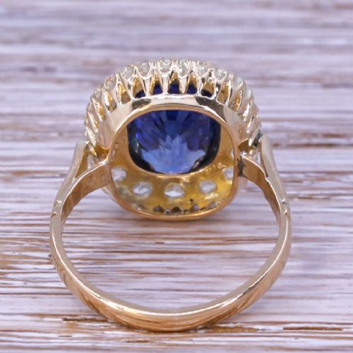 fig 3. An Art Deco yellow gold ring featuring a central cushion-cut blue sapphire framed by a halo of small diamonds.