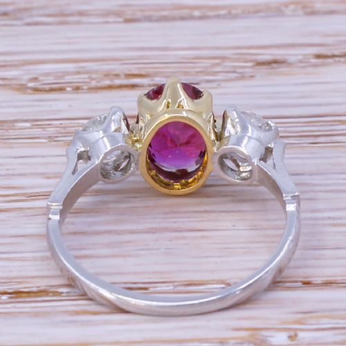 fig 3. An Art Deco three-stone ring featuring a central oval cut red ruby claw-set alongside two round diamonds on a silver-coloured metal band.