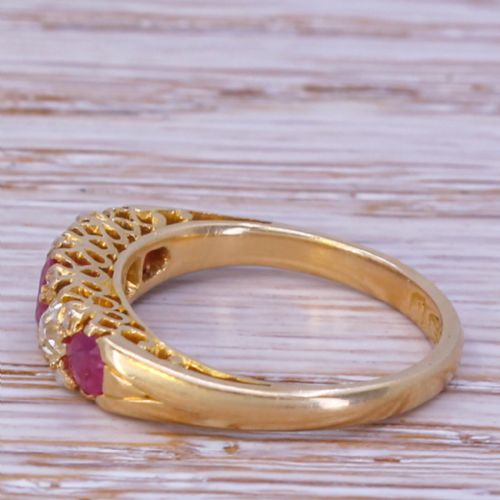fig 2. An Art Deco yellow gold ring featuring three round red rubies alternating with two diamonds in a carved gallery setting.