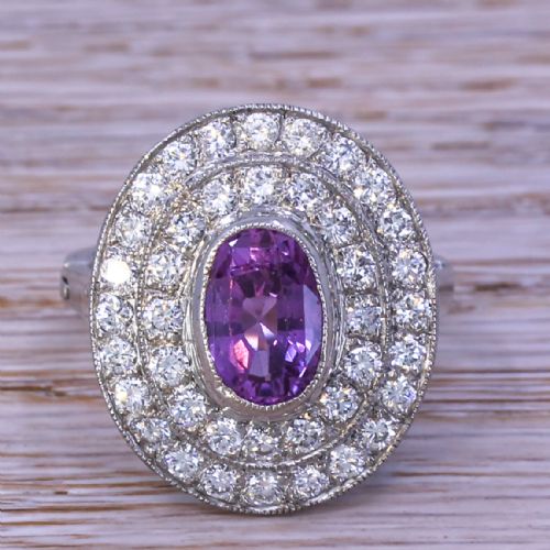 fig 1. An oval purple sapphire mounted within a double halo of brilliant-cut diamonds on a platinum ring band.