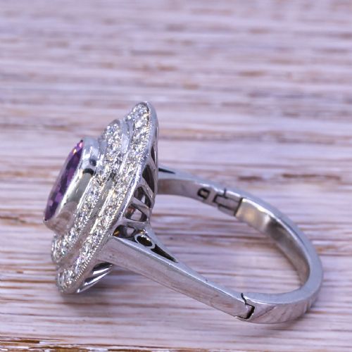 fig 2. An oval purple sapphire mounted within a double halo of brilliant-cut diamonds on a platinum ring band.