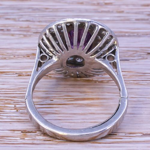 fig 3. An oval purple sapphire mounted within a double halo of brilliant-cut diamonds on a platinum ring band.