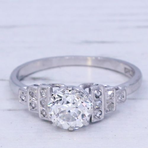 fig 2. An Art Deco platinum engagement ring featuring a central round old European cut diamond flanked by geometric stepped shoulders set with accent diamonds.
