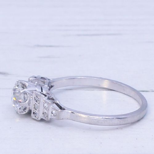 fig 3. An Art Deco platinum engagement ring featuring a central round old European cut diamond flanked by geometric stepped shoulders set with accent diamonds.