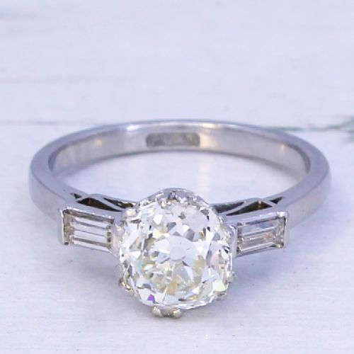 fig 2. An Art Deco platinum engagement ring featuring a central round old cut diamond flanked by two rectangular baguette diamonds.
