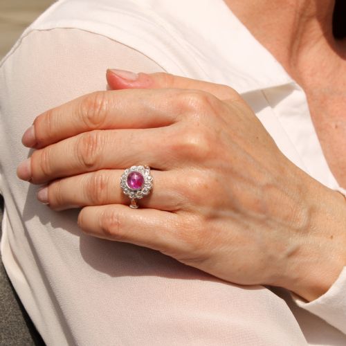 fig 1. An Art Deco platinum ring featuring a central cabochon ruby surrounded by a cluster halo of round diamonds.