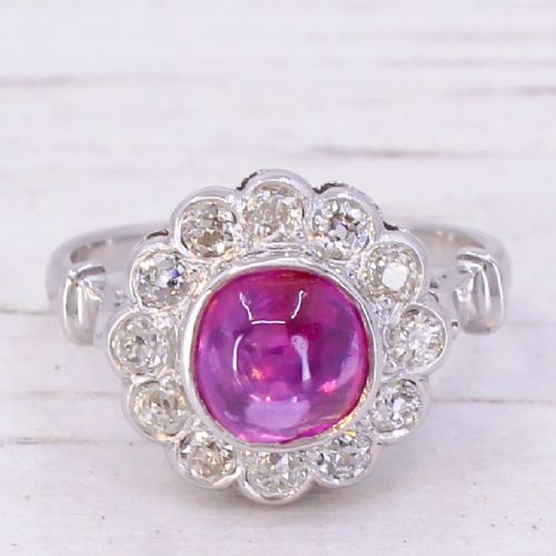 fig 2. An Art Deco platinum ring featuring a central cabochon ruby surrounded by a cluster halo of round diamonds.
