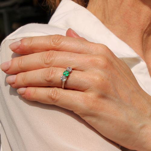 fig 1. An Art Deco three-stone ring featuring a central square-cut green emerald flanked by two round diamonds on a platinum band.