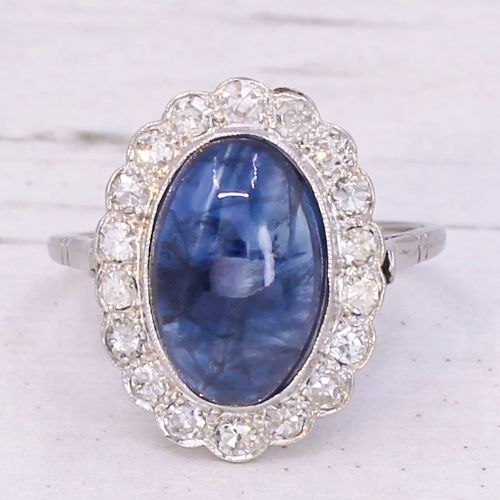 fig 2. An Art Deco ring featuring an oval cabochon blue sapphire surrounded by a halo of diamonds set in a platinum band.