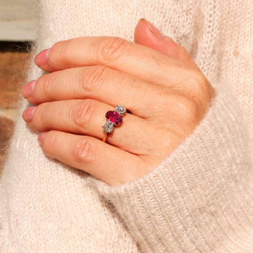 fig 1. An Art Deco three-stone ring featuring a central oval red ruby flanked by two round diamonds on a yellow gold band with platinum claw settings.