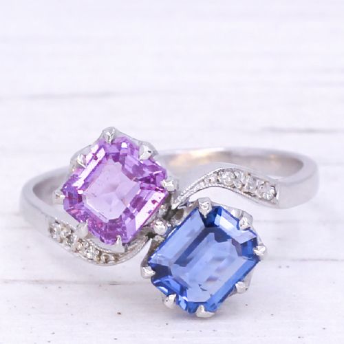 fig 2. An Art Deco platinum crossover ring set with a square-cut blue sapphire and a square-cut pink sapphire flanked by small diamonds on a curved band.
