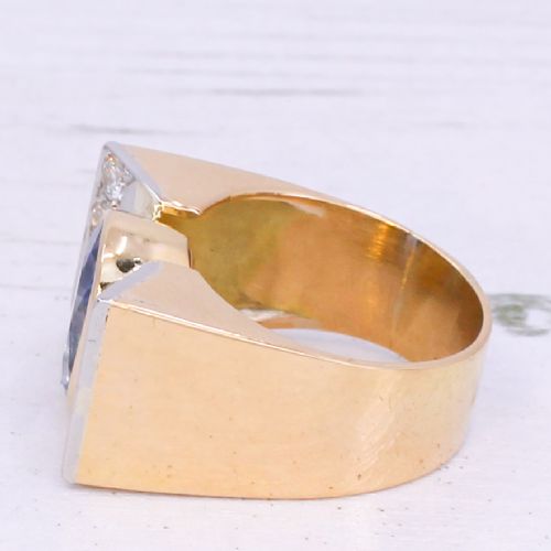 fig 3. A mid-century gold ring featuring a central oval blue sapphire set in a wide band with diamond-set vertical shoulders.