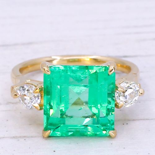 fig 2. An Edwardian yellow gold trilogy ring set with a large square step-cut green emerald flanked by two round diamonds.