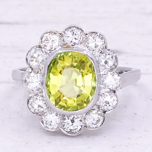 fig 2. An Art Deco ring featuring an oval yellow-green chrysoberyl gemstone encircled by a halo of round diamonds set in platinum.